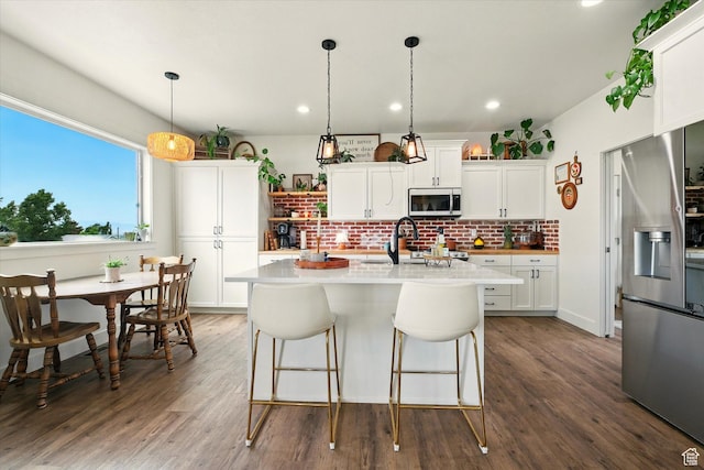 155 N 200 E, Richmond, UT 84333 - kitchen featuring appliances with stainless steel finishes, backsplash, light countertops, dark wood-style floors, and an island with sink