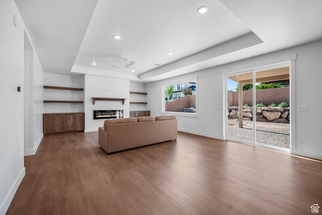 2154 S Bluff Dr, Cedar City, UT 84720 - living area with a tray ceiling, a glass covered fireplace, dark wood finished floors, plenty of natural light, and recessed lighting