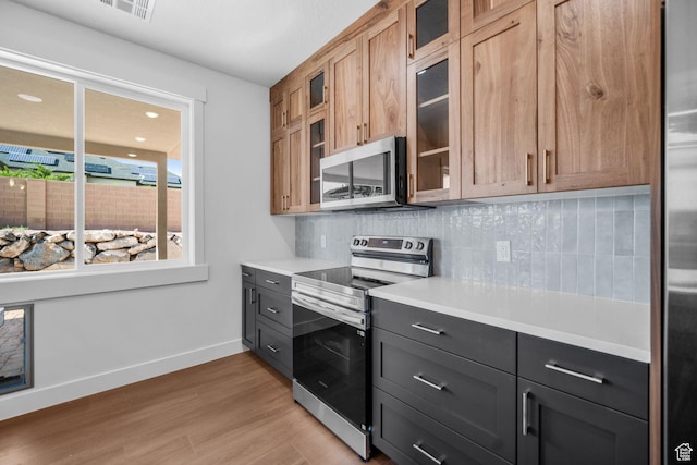 2154 S Bluff Dr, Cedar City, UT 84720 - kitchen with appliances with stainless steel finishes, decorative backsplash, light countertops, light wood-type flooring, and glass insert cabinets