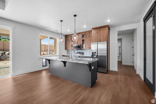 2154 S Bluff Dr, Cedar City, UT 84720 - kitchen with appliances with stainless steel finishes, brown cabinets, a kitchen bar, dark wood-style floors, and recessed lighting