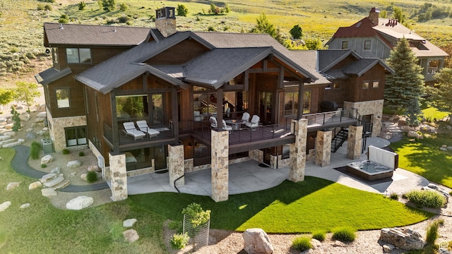 3911 N Zermatt St, Eden, UT 84310 - rear view of house with stone siding, a patio area, a chimney, a deck, and a lawn
