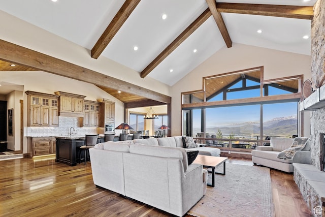 3911 N Zermatt St, Eden, UT 84310 - living room with a mountain view, beam ceiling, wood finished floors, a chandelier, and a stone fireplace