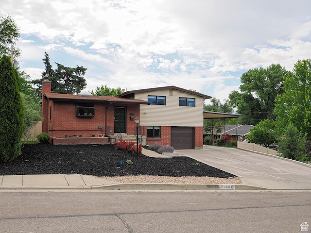4601 S Creekview Cir, Murray, UT 84107 - tri-level home featuring brick siding, concrete driveway, an attached garage, a carport, and a chimney