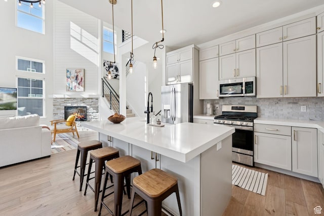 12756 N Belaview Way, Hideout, UT 84036 - kitchen featuring stainless steel appliances, a towering ceiling, light wood-style flooring, decorative backsplash, and light countertops