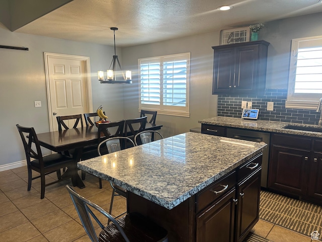 1295 S 4050 W, Syracuse, UT 84075 - kitchen featuring plenty of natural light, light tile patterned flooring, a kitchen bar, a center island, and a textured ceiling
