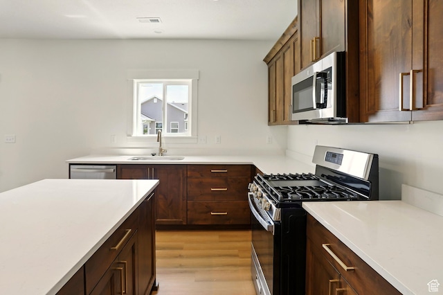 1154 E 1150 S, Garland, UT 84312 - kitchen with appliances with stainless steel finishes, light countertops, light wood finished floors, and dark brown cabinets