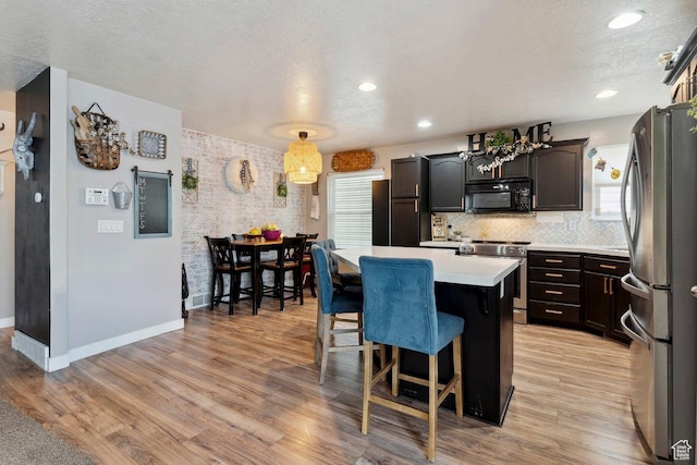 2536 S Andover St, West Haven, UT 84401 - kitchen featuring appliances with stainless steel finishes, a kitchen island, a textured ceiling, light countertops, and a breakfast bar area