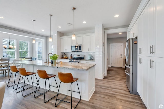 10616 S Wistful Way S, Jordan, UT 84009 - kitchen with stainless steel appliances, white cabinetry, a kitchen breakfast bar, and recessed lighting