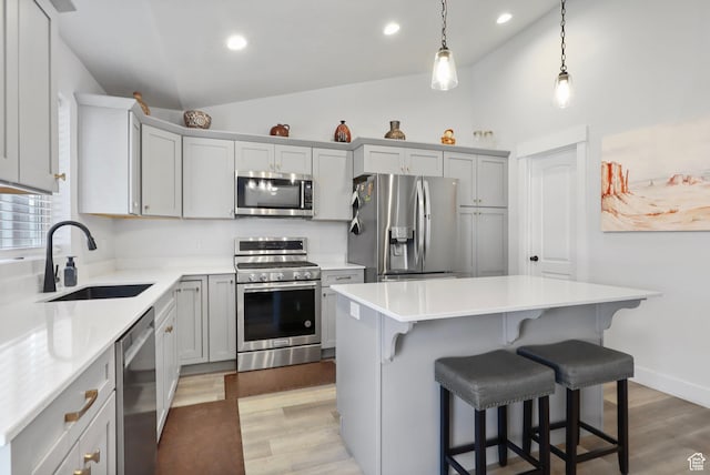 4764 N Gunsight Peak Dr, Eagle Mountain, UT 84005 - kitchen with appliances with stainless steel finishes, light wood-style floors, a kitchen bar, a kitchen island, and light countertops