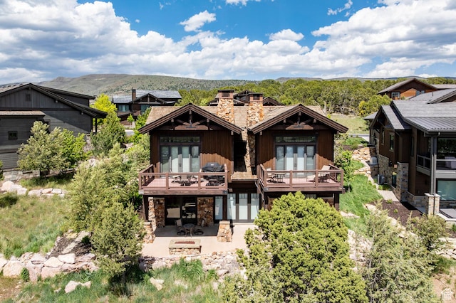285 N Kings Peak Ct, Heber City, UT 84032 - rear view of house with stone siding, french doors, a patio area, a chimney, and a deck with mountain view