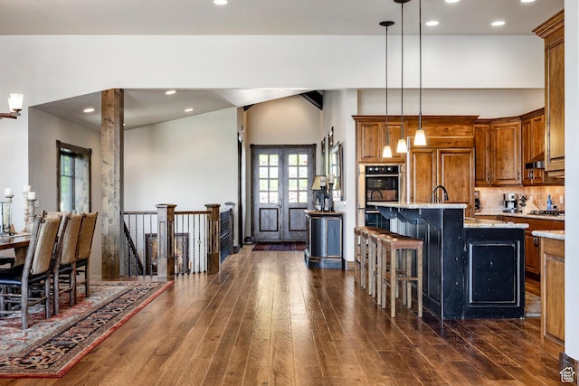 285 N Kings Peak Ct, Heber City, UT 84032 - kitchen featuring brown cabinetry, appliances with stainless steel finishes, dark wood-type flooring, a breakfast bar, and an island with sink