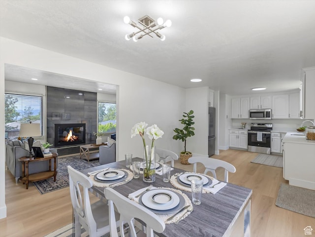 8359 S Fayeway Dr, Sandy, UT 84094 - dining space featuring plenty of natural light, light wood-style flooring, a tile fireplace, and recessed lighting