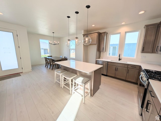 7071 W Granbury Dr S Unit 258, South Jordan, UT 84009 - kitchen with appliances with stainless steel finishes, a kitchen breakfast bar, a chandelier, hanging light fixtures, and light wood finished floors