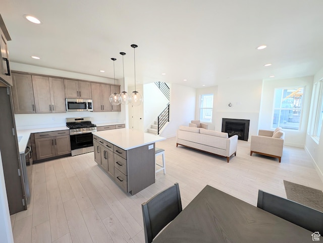 7071 W Granbury Dr S Unit 258, South Jordan, UT 84009 - kitchen featuring appliances with stainless steel finishes, light wood-type flooring, a kitchen bar, light countertops, and open floor plan