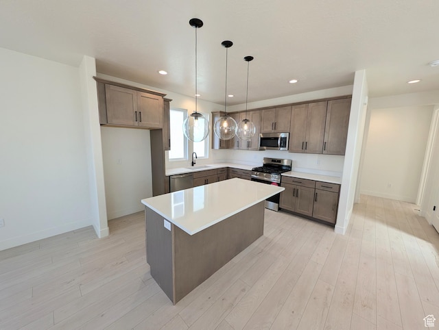 7071 W Granbury Dr S Unit 258, South Jordan, UT 84009 - kitchen with appliances with stainless steel finishes, light wood-style flooring, light countertops, pendant lighting, and a kitchen island