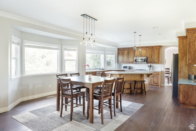 9788 S Dante Rd E, Sandy, UT 84092 - dining space featuring dark wood finished floors, ornamental molding, arched walkways, and recessed lighting