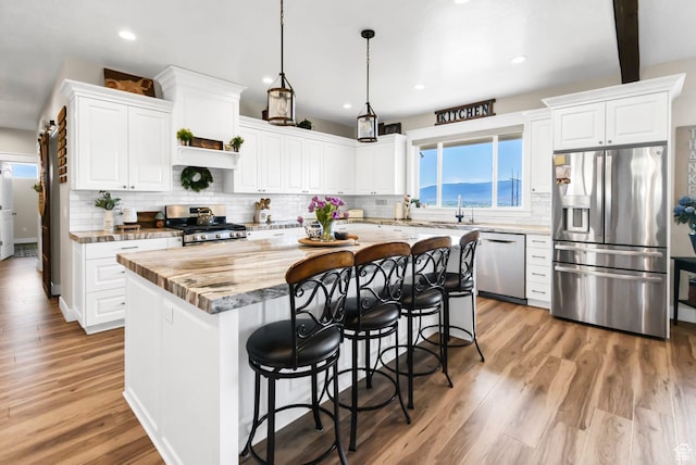 2253 N 1200 E, Monroe, UT 84754 - kitchen featuring appliances with stainless steel finishes, a kitchen island, a breakfast bar, white cabinets, and light wood finished floors