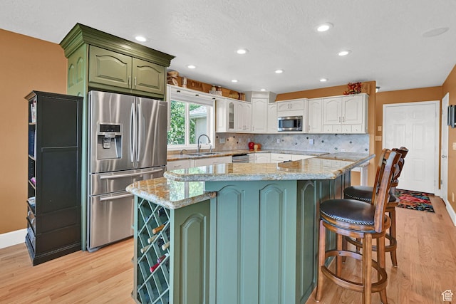 1269 Alice Ln, Farmington, UT 84025 - kitchen featuring stainless steel appliances, green cabinets, light wood finished floors, backsplash, and recessed lighting