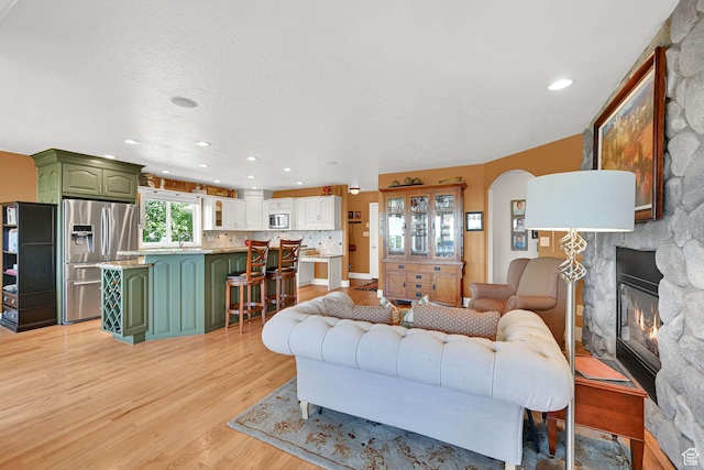 1269 Alice Ln, Farmington, UT 84025 - living area featuring light wood-style flooring, a stone fireplace, recessed lighting, and arched walkways