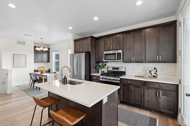 5504 W Burntside Ave, South Jordan, UT 84009 - kitchen featuring stainless steel appliances, tasteful backsplash, dark brown cabinetry, a chandelier, and light countertops