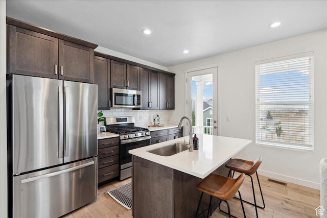 5504 W Burntside Ave, South Jordan, UT 84009 - kitchen featuring appliances with stainless steel finishes, light wood-style floors, dark brown cabinetry, tasteful backsplash, and recessed lighting