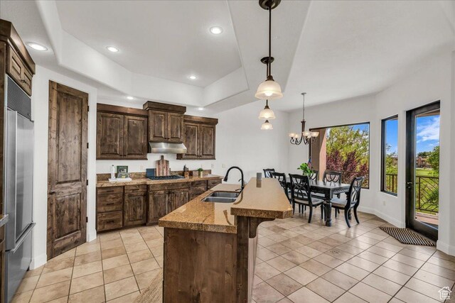 1683 W Red Cloud Dr, St George, UT 84770 - kitchen with stainless steel built in refrigerator, under cabinet range hood, dark brown cabinetry, a kitchen breakfast bar, and a tray ceiling