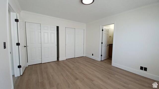6116 W Graceland Way, West Jordan, UT 84081 - unfurnished bedroom featuring multiple closets, light wood-style floors, ornamental molding, and ensuite bath