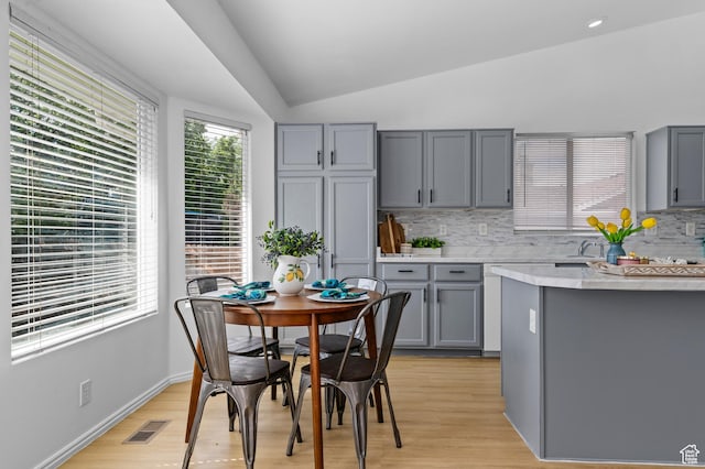9152 S Crystal Vista Ln, West Jordan, UT 84088 - kitchen featuring gray cabinetry, lofted ceiling, light countertops, tasteful backsplash, and light wood-style floors