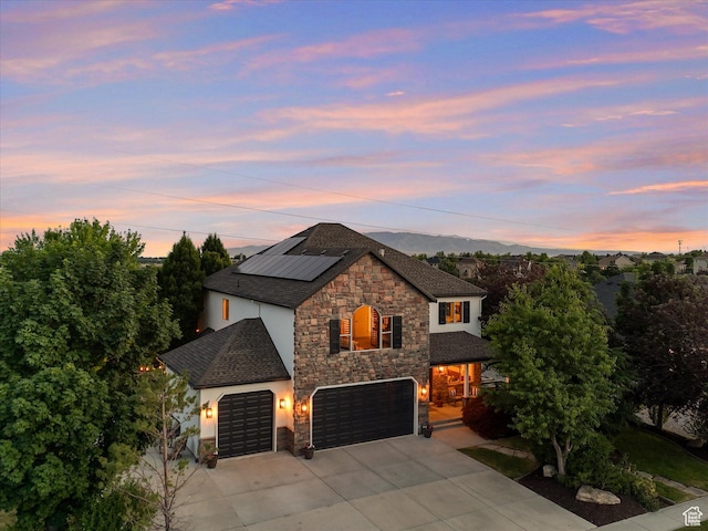 6037 Chamberry Way N, Highland, UT 84003 - view of front of property featuring stone siding, concrete driveway, roof mounted solar panels, and stucco siding