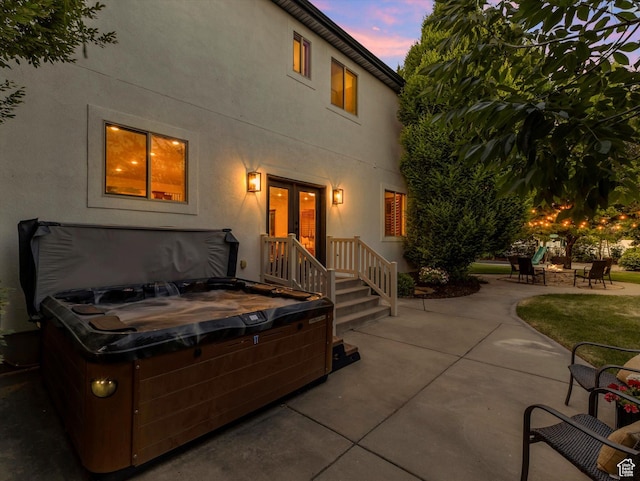6037 Chamberry Way N, Highland, UT 84003 - back of property at dusk with a hot tub, a patio, stucco siding, and a fire pit