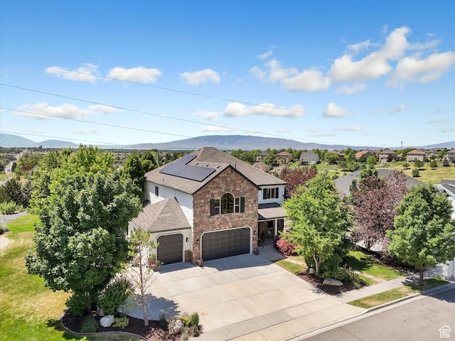 6037 Chamberry Way N, Highland, UT 84003 - view of front of home featuring stone siding, roof mounted solar panels, driveway, a shingled roof, and a mountain view