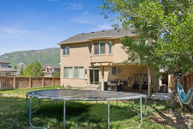 15106 S Heather Stone Cir, Draper, UT 84020 - back of house featuring a trampoline, stucco siding, a fenced backyard, a mountain view, and a pergola