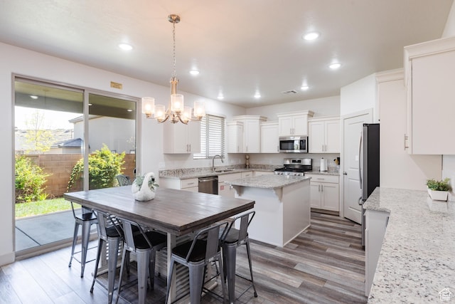 344 N Puerta Dr, Washington, UT 84780 - kitchen with appliances with stainless steel finishes, a chandelier, a center island, white cabinets, and light wood-style floors