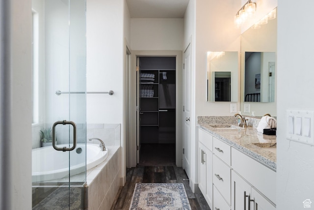 344 N Puerta Dr, Washington, UT 84780 - bathroom with double vanity, a bath, wood finished floors, a shower stall, and a walk in closet