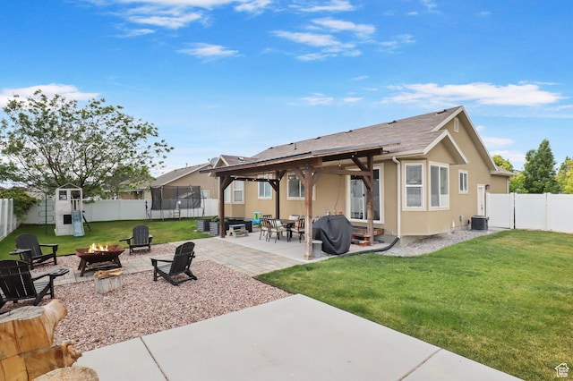 448 Lourdes Ln, Stansbury Park, UT 84074 - back of house with an outdoor fire pit, a trampoline, a fenced backyard, and a patio