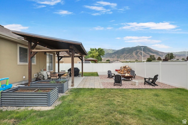 448 Lourdes Ln, Stansbury Park, UT 84074 - fenced backyard featuring a mountain view, a patio, an outdoor fire pit, and a vegetable garden