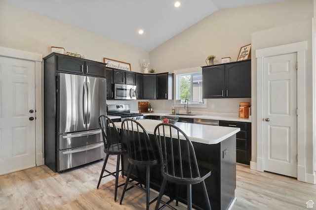 448 Lourdes Ln, Stansbury Park, UT 84074 - kitchen with appliances with stainless steel finishes, vaulted ceiling, a breakfast bar, light countertops, and a kitchen island