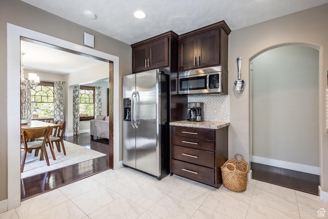 1603 S 1600 E, Salt Lake City, UT 84105 - kitchen with appliances with stainless steel finishes, arched walkways, dark brown cabinetry, tasteful backsplash, and light stone countertops