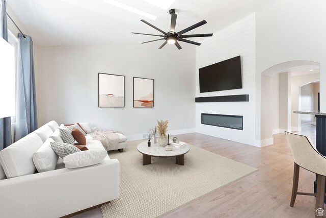 8743 N Franklin Dr E, Eagle Mountain, UT 84005 - living room featuring ceiling fan, arched walkways, light wood-style floors, a fireplace, and high vaulted ceiling