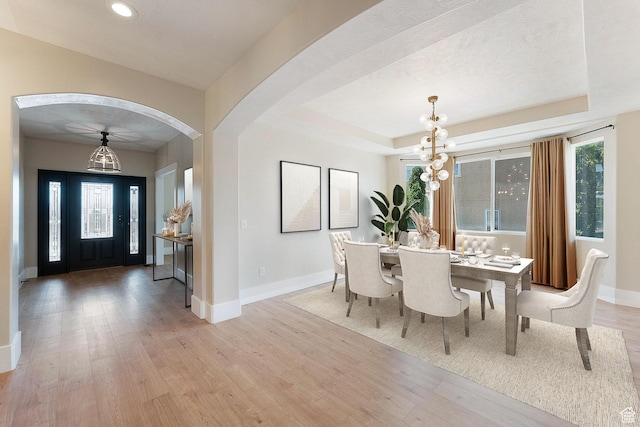 8743 N Franklin Dr E, Eagle Mountain, UT 84005 - dining room with light wood-style flooring, a chandelier, arched walkways, recessed lighting, and a tray ceiling