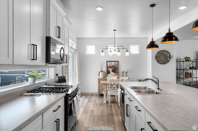 106 E Polaris Dr, Saratoga Springs, UT 84045 - kitchen featuring appliances with stainless steel finishes, light countertops, light wood finished floors, pendant lighting, and white cabinetry