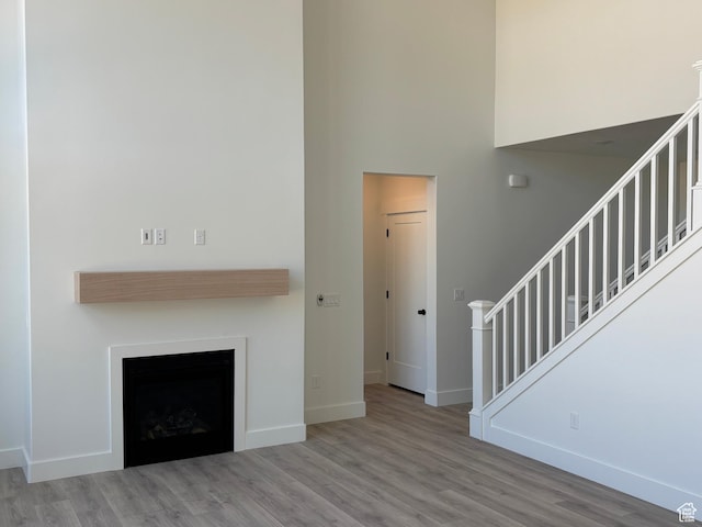 1678 S 130 W Unit 48, Salem, UT 84653 - unfurnished living room with stairs, wood finished floors, a fireplace, and a towering ceiling