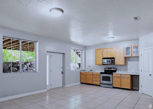 3903 S 3200 W, West Valley City, UT 84119 - kitchen featuring appliances with stainless steel finishes, light countertops, a textured ceiling, glass insert cabinets, and light tile patterned flooring