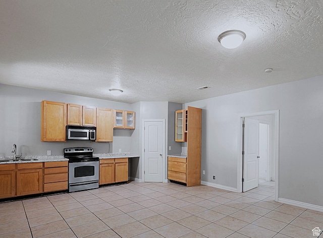 3903 S 3200 W, West Valley City, UT 84119 - kitchen with stainless steel appliances, light countertops, glass insert cabinets, light tile patterned floors, and a textured ceiling