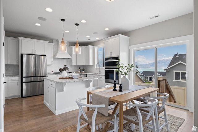 3256 S Iron Hill Cir, Saratoga Springs, UT 84045 - kitchen featuring stainless steel appliances, wall chimney range hood, decorative backsplash, a center island, and recessed lighting