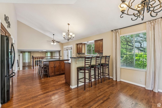 1087 W Barnes Dr, Kaysville, UT 84037 - kitchen with a chandelier, fridge with ice dispenser, brown cabinets, dark countertops, and vaulted ceiling