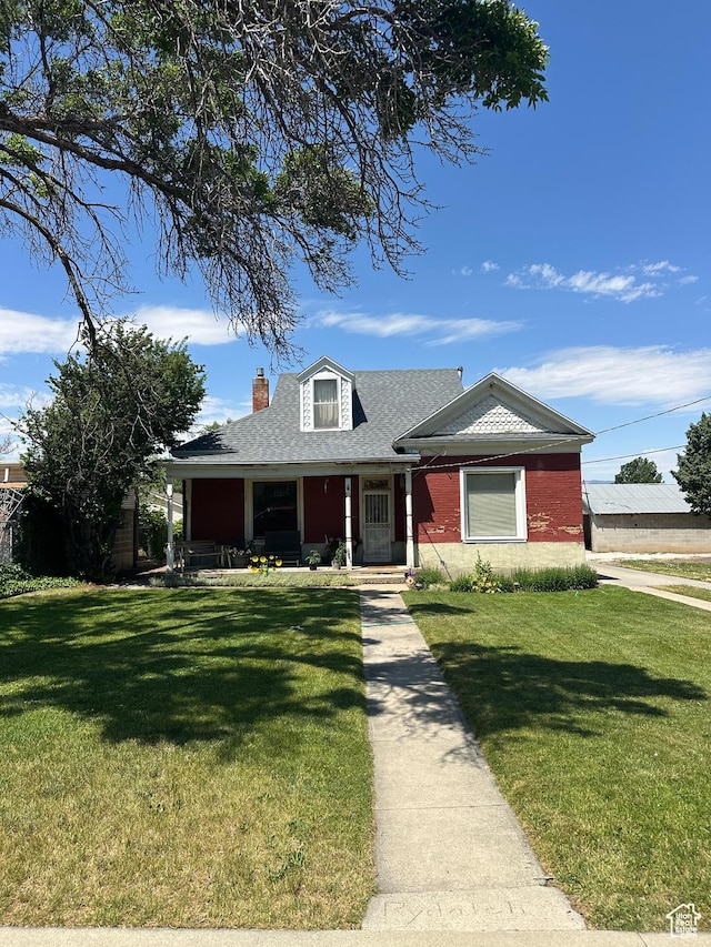 225 N 200 W, Tooele, UT 84074 - view of front of home featuring a porch, a front yard, a chimney, roof with shingles, and brick siding