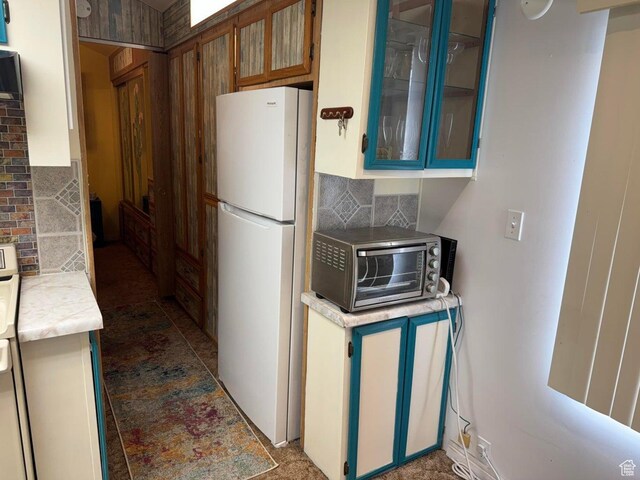 1225 N Dixie Downs Rd Unit 100, St George, UT 84770 - kitchen with freestanding refrigerator, backsplash, light countertops, and brown cabinets