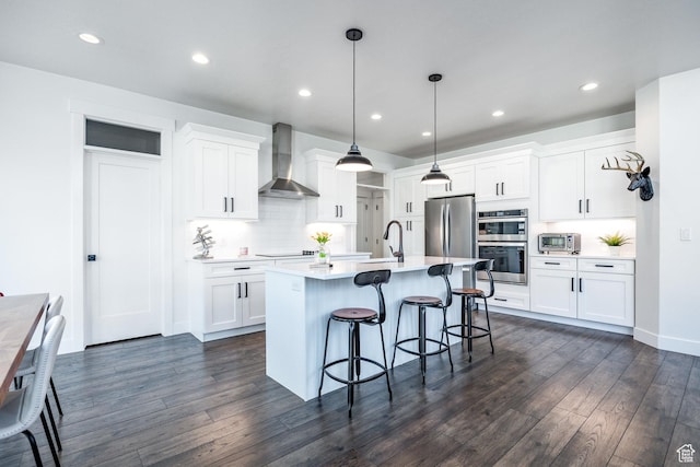 2452 E Lone Hill Dr Unit 324, Draper Ut Cnty, UT 84020 - kitchen featuring wall chimney range hood, stainless steel appliances, a kitchen bar, dark wood-style floors, and recessed lighting