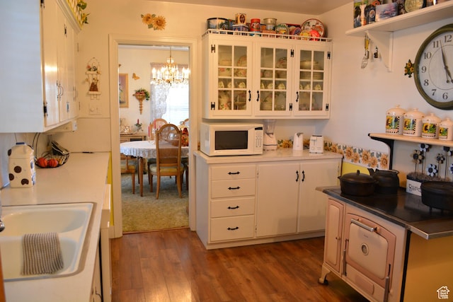 114 W 7th St, Georgetown, ID 83239 - kitchen with white microwave, a chandelier, wood finished floors, white cabinetry, and glass insert cabinets